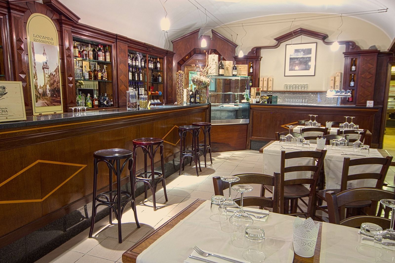 La sala della Locanda Rossignoli con il bancone in legno e i tavoli apparecchiati